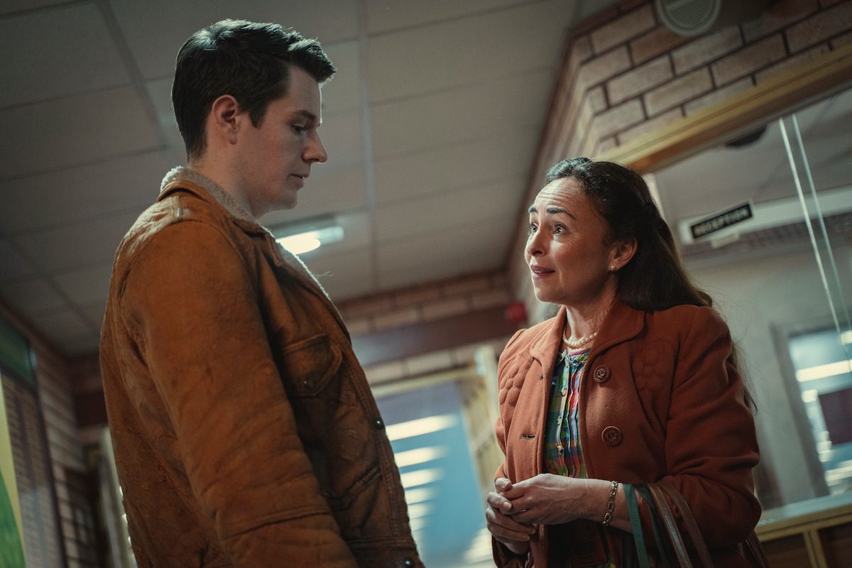 Connor Swindells as Adam Groff and Samantha Spiro as Maureen Groff stand together in a school hallway in ‘Sex Education’
