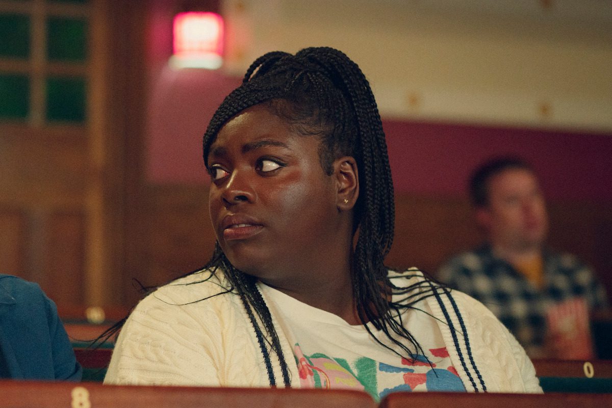 Chinenye Ezeudu as Viv sits in an auditorium in Season 4 of ‘Sex Education.’