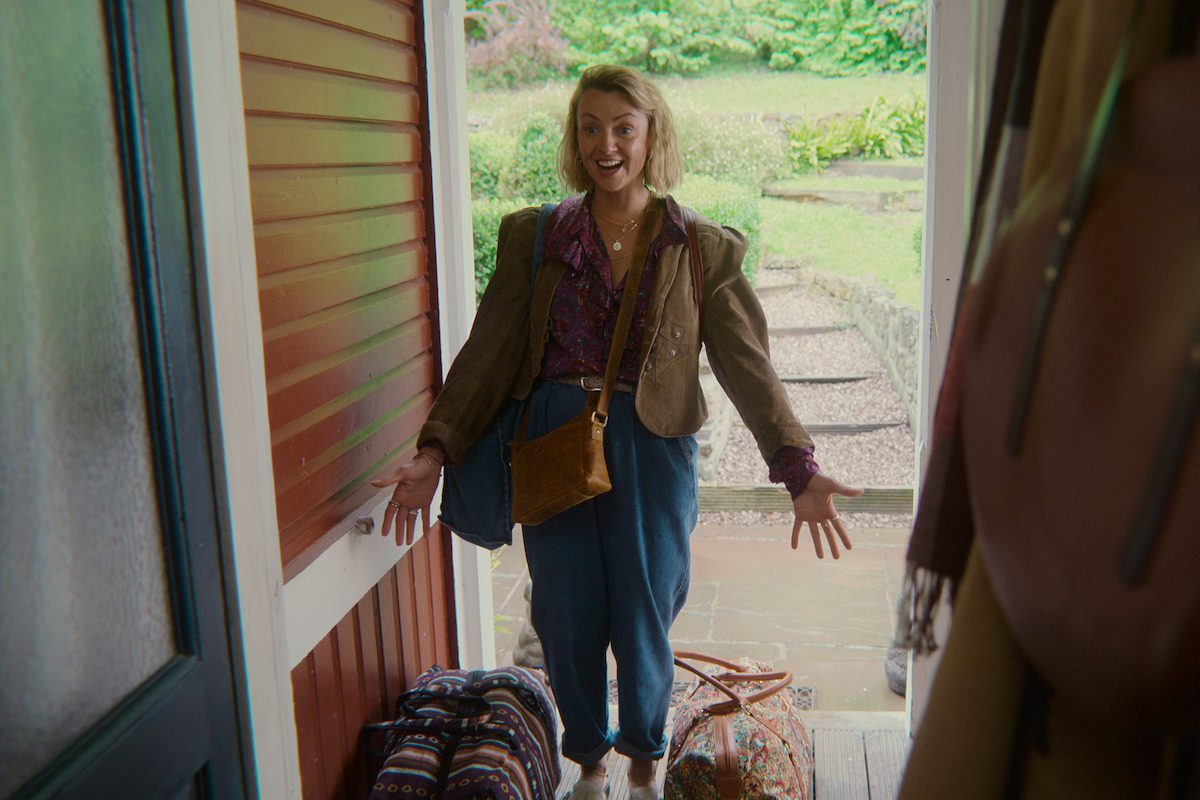 Lisa McGrillis as Joanna stands in a doorway with open arms in Season 4 of ‘Sex Education.’