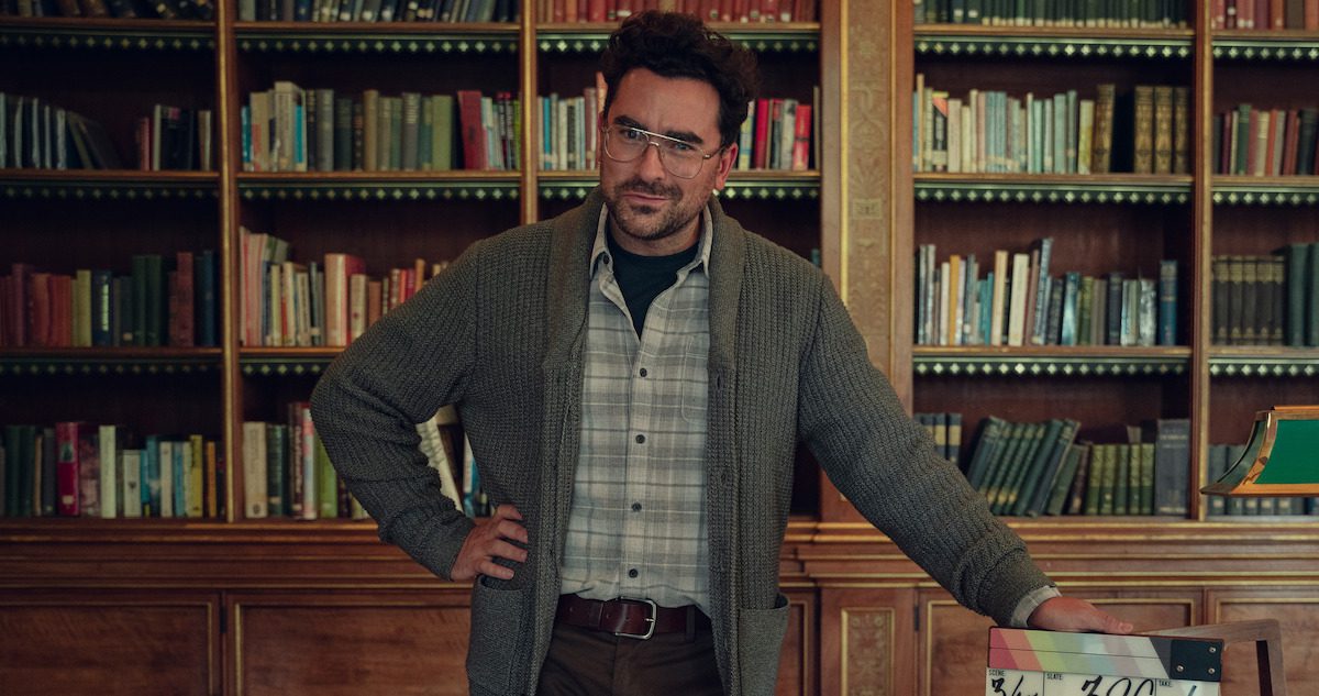 Dan Levy as Thomas Molloy stands in an office in Season 4 of ‘Sex Education.’