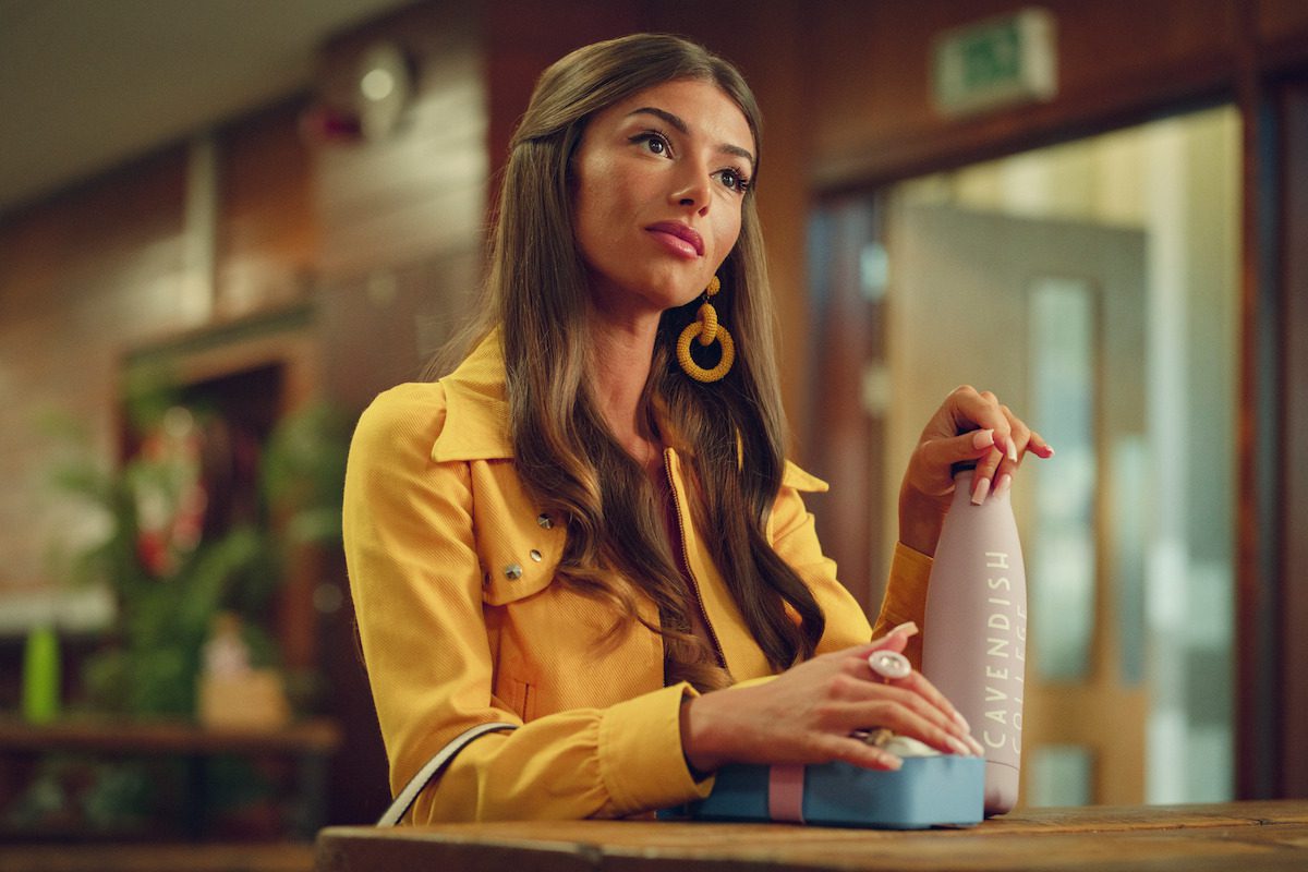 Mimi Keene as Ruby Matthews sits at a desk holding a water bottle in Season 4 of ‘Sex Education’
